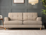 Beige plaid sofa in a room with a gray wall and wooden floor.
